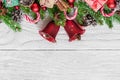 Christmas background with fir tree, christmas bells, candy, gift boxes, berries and pine cones on white wooden table Royalty Free Stock Photo