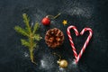 Christmas background. Fir tree branch, cone, candy canes, balls, on a black snowy background.