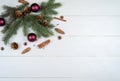 Christmas background with fir tree branches, glass balls, pine cones, cinnamon sticks and star anise on white wooden background Royalty Free Stock Photo