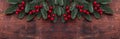 Christmas background with fir tree branches and holly. Top view. Horizontal banner. Copy space Royalty Free Stock Photo