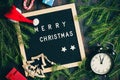 Christmas background. Christmas fir tree branches with vintage alarm clock and giftboxes on rustic wooden board near letter board