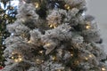 Christmas background of flocked tree with white lights with dark green bokeh tree in background