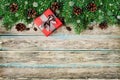 Christmas background with gift box, fir branch and conifer cone on wooden rustic board, festive snow effect, Christmas frame Royalty Free Stock Photo