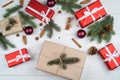 Christmas background with gift boxes, fir tree branches, pine cones, cinnamon sticks and stars anise on white wooden background. Royalty Free Stock Photo
