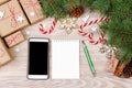 Christmas background with gift boxes, mobile phone with back screen and blank notebook, copy space. Template for new year goal or Royalty Free Stock Photo