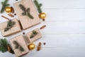 Christmas background with gift boxes wrapped in kraft paper with fir tree branches and cones on white wooden background. Royalty Free Stock Photo