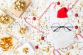 Christmas background of golden confetti, gift or present boxes and funny Santa on white table top view. Flat lay. Royalty Free Stock Photo
