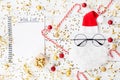 Christmas background of golden confetti, gift or present boxes, wish list notebook and funny Santa on table top view. Flat lay. Royalty Free Stock Photo