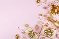 Christmas background with golden gift or present box, champagne and holiday decorations on pink pastel table top view. Flat lay. Royalty Free Stock Photo