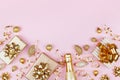 Christmas background with golden gift or present box, champagne and holiday decorations on pink pastel table top view. Flat lay. Royalty Free Stock Photo