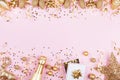 Christmas background with golden gift or present box, champagne and holiday decorations on pink pastel table top view. Flat lay. Royalty Free Stock Photo