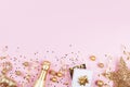 Christmas background with golden gift or present box, champagne and holiday decorations on pink pastel table top view. Flat lay. Royalty Free Stock Photo