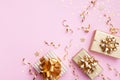 Christmas background. Golden gift or present boxes and star confetti on pink top view. Flat lay Royalty Free Stock Photo