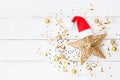 Christmas background of golden star with Santa hat, holiday decorations and confetti top view. Flat lay Royalty Free Stock Photo