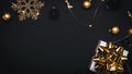 Christmas background golden. White gift box with golden ribbon, New Year balls and sparkling lights garland in xmas composition on Royalty Free Stock Photo