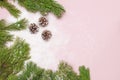 Christmas background, green pine branches, cones decorated with snow on snowy pink background. Creative composition with border Royalty Free Stock Photo