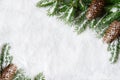 Christmas background, green pine branches, cones on snow background. Creative composition with border and copy space, top view. Royalty Free Stock Photo