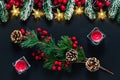 Christmas background with green spruce branches, pine cones and holly berries on a black backdrop. Festive template, postcard with