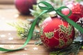 Christmas background, greeting card. Red beautiful bauble with green ribbon, fir branches, winter decoration, gift boxes over Royalty Free Stock Photo