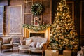 Christmas background with illuminated fir tree with golden decpration and fireplace in living room. Cozy holiday home