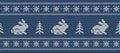 Christmas background. Knitted pattern with hares and christmas trees on a blue background