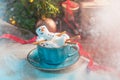 Christmas background with a marshmallow man lying in a mug with cocoa, in the background a Christmas tree with toys, a garland and Royalty Free Stock Photo