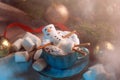 Christmas background with a marshmallow man lying in a mug with cocoa, in the background a Christmas tree with toys, a garland and Royalty Free Stock Photo