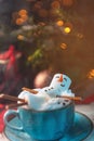 Christmas background with a marshmallow man lying in a mug with cocoa, in the background a Christmas tree with toys, a garland and Royalty Free Stock Photo