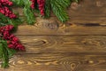 Christmas background. Nobilis fir branches, twigs with red berries on brown wooden planks. Copy space, flat lay, top view. Holiday Royalty Free Stock Photo