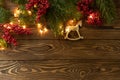 Christmas background. Nobilis fir branches, twigs with red berries, toy golden horse on brown wooden planks. Copy space, flat lay Royalty Free Stock Photo