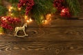 Christmas background. Nobilis fir branches, twigs with red berries, toy golden horse on brown wooden planks. Copy space, flat lay Royalty Free Stock Photo