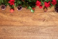 Christmas background with pine branches, red flowers, and cones on wooden board with copy space. Top view Royalty Free Stock Photo