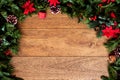 Christmas background with pine branches, red flowers, and cones on wooden board with copy space. Top view Royalty Free Stock Photo