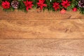 Christmas background with pine branches, red flowers, and cones on wooden board with copy space. Top view Royalty Free Stock Photo