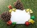 Christmas background pine cone gift boxes, bells and space for writing your message on green grass. Royalty Free Stock Photo