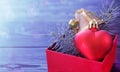 Christmas background: red gift box with a Christmas toy in the form of a heart, a golden bell and fir branches Royalty Free Stock Photo