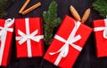 Christmas background with red gift boxes, fir tree branches and cones on dark wooden table, top view, flat lay. Royalty Free Stock Photo