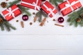 Christmas background with red gift boxes, fir tree branches, pine cones, cinnamon sticks and stars anise on white wooden. Royalty Free Stock Photo