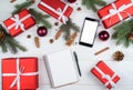 Christmas background with red gift boxes, mobile phone with white screen and blank notebook, copy space. Template for new year. Royalty Free Stock Photo