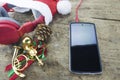 Christmas background. Red headphone in santa Claus hat, smart phone and christmas decoration staff on wooden background Royalty Free Stock Photo