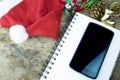 Christmas background. Red headphone in santa Claus hat, smart phone and christmas decoration staff on wooden background Royalty Free Stock Photo