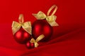 Christmas background in rich luxury style - shiny red balls, gold ribbon on scarlet silk curtain with smooth creases, copy space. Royalty Free Stock Photo