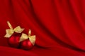 Christmas background in rich luxury style - two shiny red balls, gold ribbon on scarlet silk curtain with smooth creases. Royalty Free Stock Photo