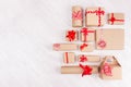 Christmas background - set of various craft paper gifts with red ribbons and bows on soft light white wood board, flat lay.