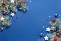 Christmas background with snow fir branches, shiny red balls, blue and white stars on a blue Royalty Free Stock Photo