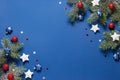 Christmas background with snow fir branches, shiny red balls, blue and white stars on a blue Royalty Free Stock Photo