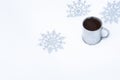 Christmas background with snowflakes and a mug of hot coffee in the snow. Snowflakes around an old metal mug with a coffee drink