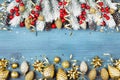 Christmas background with snowy fir tree and golden holiday decorations on blue wooden table top view. Greeting card. Royalty Free Stock Photo