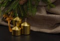 Christmas background. There are three golden candles on linen canvas. A spruce branch with cones hangs from the top Royalty Free Stock Photo