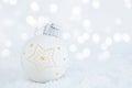 Christmas background. Christmas tree toy of white color on the snow on a background of bokeh lights. Christmas and New Year Royalty Free Stock Photo